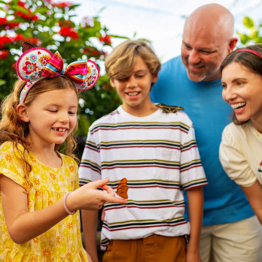 A family of 4 interacting with a butterfly at the Epcot International Flower and Garden Festival