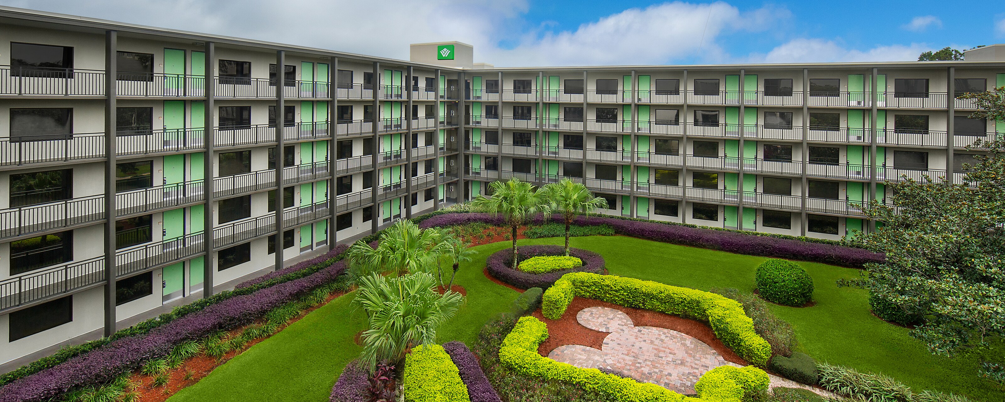 Many hotel rooms with patios overlooking a courtyard and a hot air balloon floating in the sky.