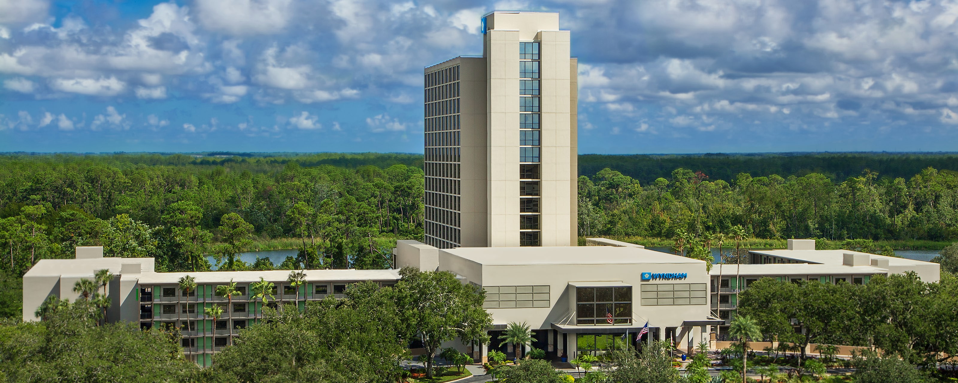 La torre de un hotel con muchas ventanas, detrás de copas de árboles circundantes