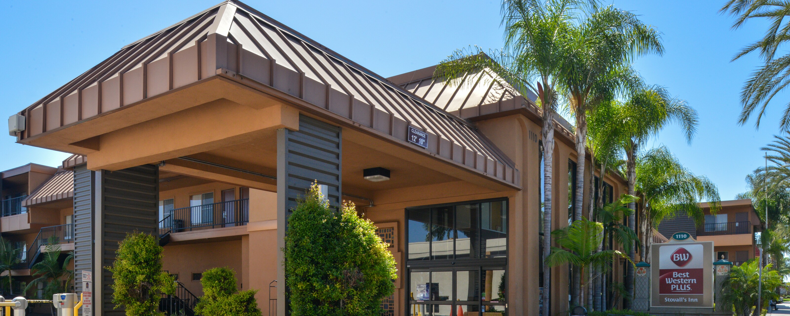 The carport overhang and entrance to Best Western Plus Stovall's Inn accented with palm trees