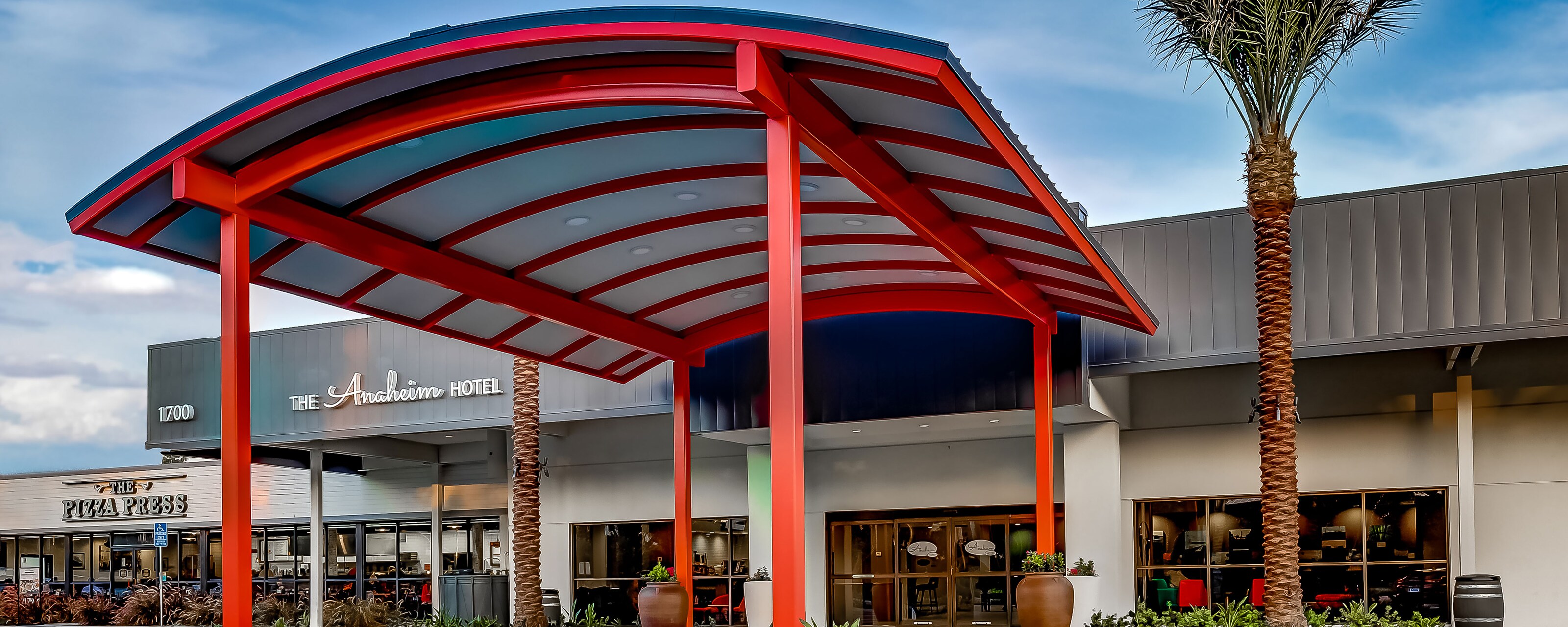 A large, rounded awning stretches out from above the lobby doors of the Anaheim Hotel
