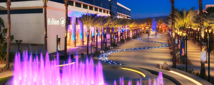 Una fuente centelleante y un arroyo sinuoso en Hilton Anaheim iluminados en la noche