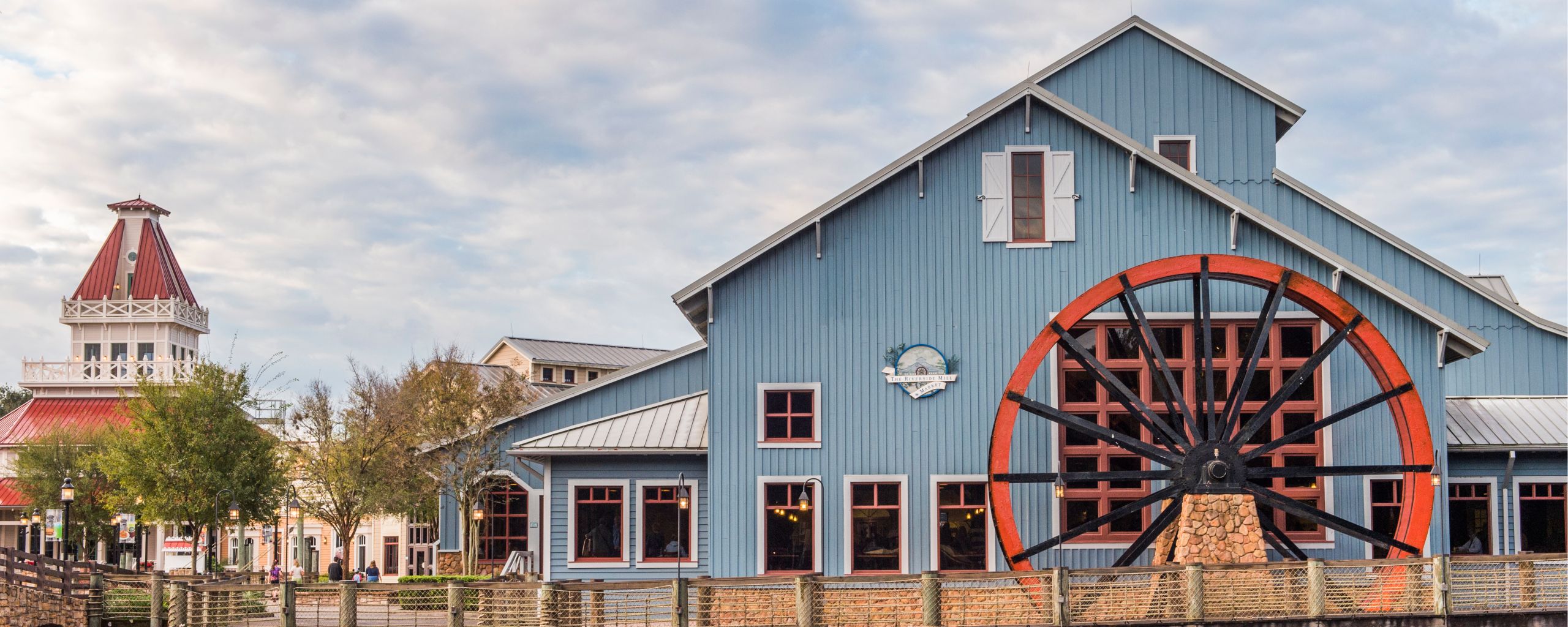 Disney’s Port Orleans Resort Riverside, a farm style building with a large water wheel and a wooden bridge, by the banks of the Sassagoula River