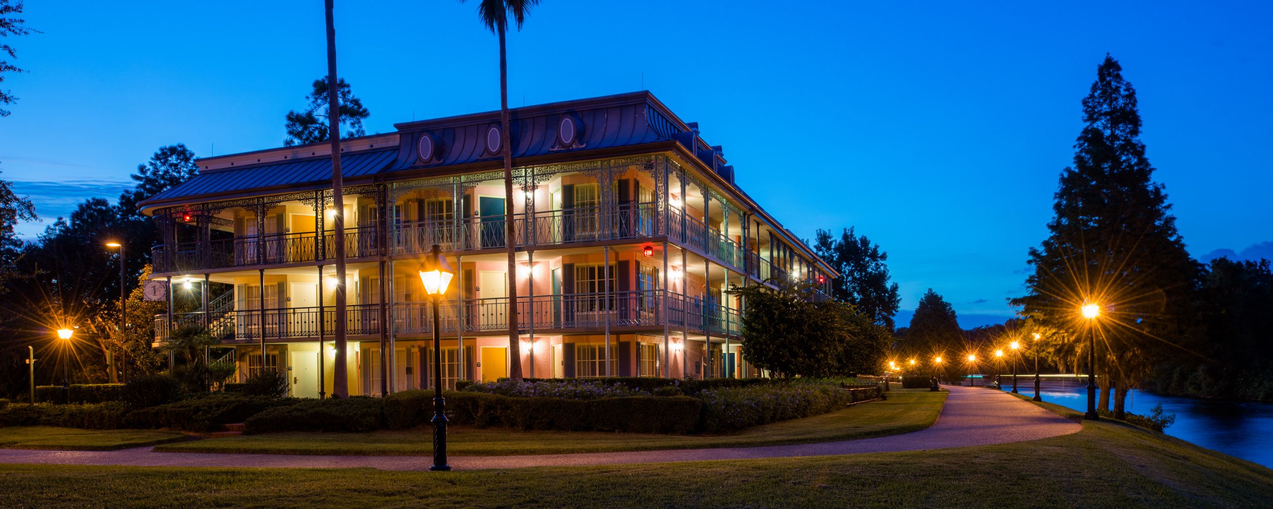 Disney’s Port Orleans Resort French Quarter, a 3 story building surrounded by a walkway and adjacent to the Sassagoula River