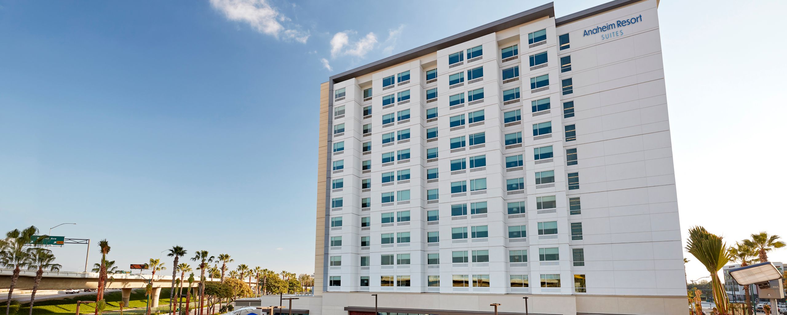 Anaheim Resort Suites hotel exterior with pool area featuring waterslides and striped umbrellas