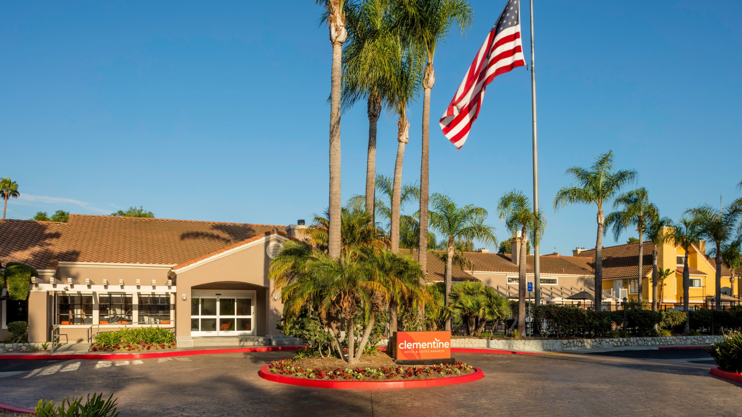 The façade of Clementine Hotel & Suites Anaheim near an American flag