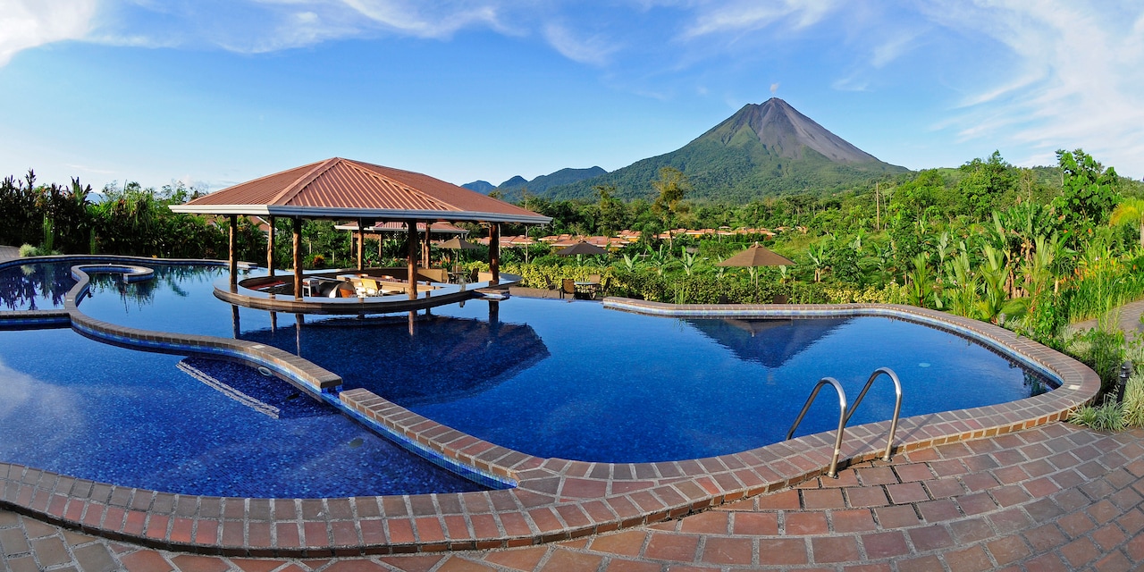 The pool at the Hotel Arenal Manoa with a swim-up bar in the middle and view of Arenal Volcano in the distance The pool at the Hotel Arenal Manoa with a swim-up bar in the middle and view of Arenal Volcano in the distance
