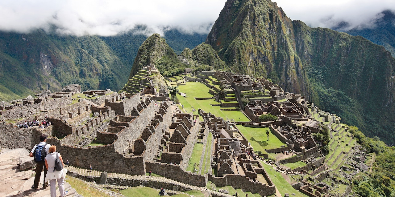 A couple stands on a stone terrace above Machu Picchu A couple stands on a stone terrace above Machu Picchu