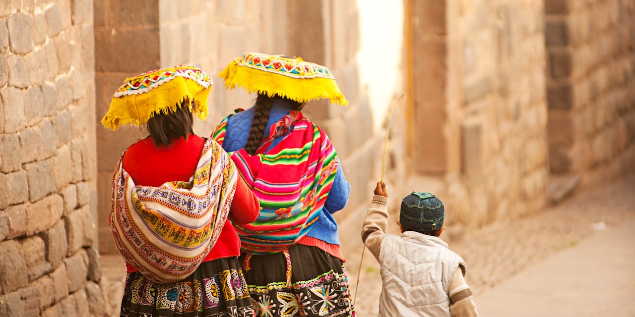 A boy walks with 2 women dressed in traditional clothes down an empty street A boy walks with 2 women dressed in traditional clothes down an empty street