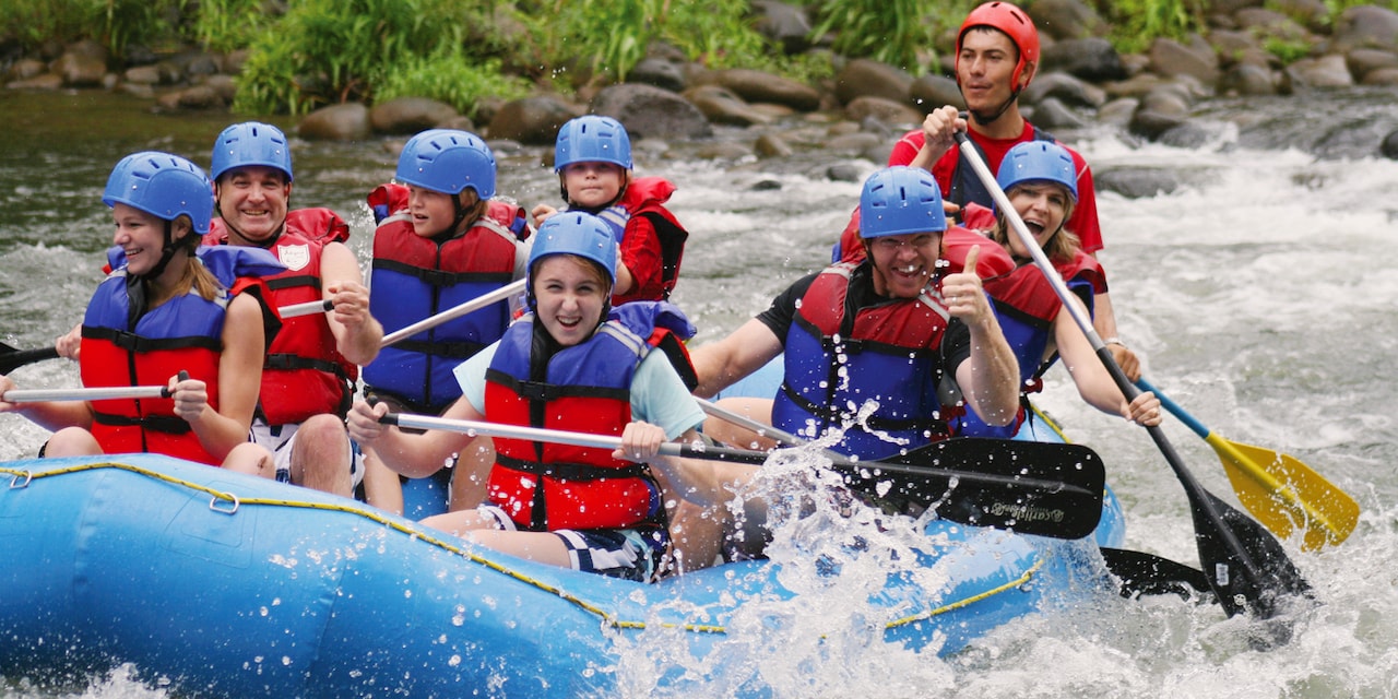 Adults and children paddle as they raft down a river Adults and children paddle as they raft down a river