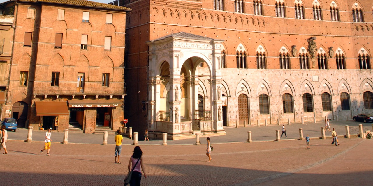 People walk down a street in Siena, Italy People walk down a street in Siena, Italy