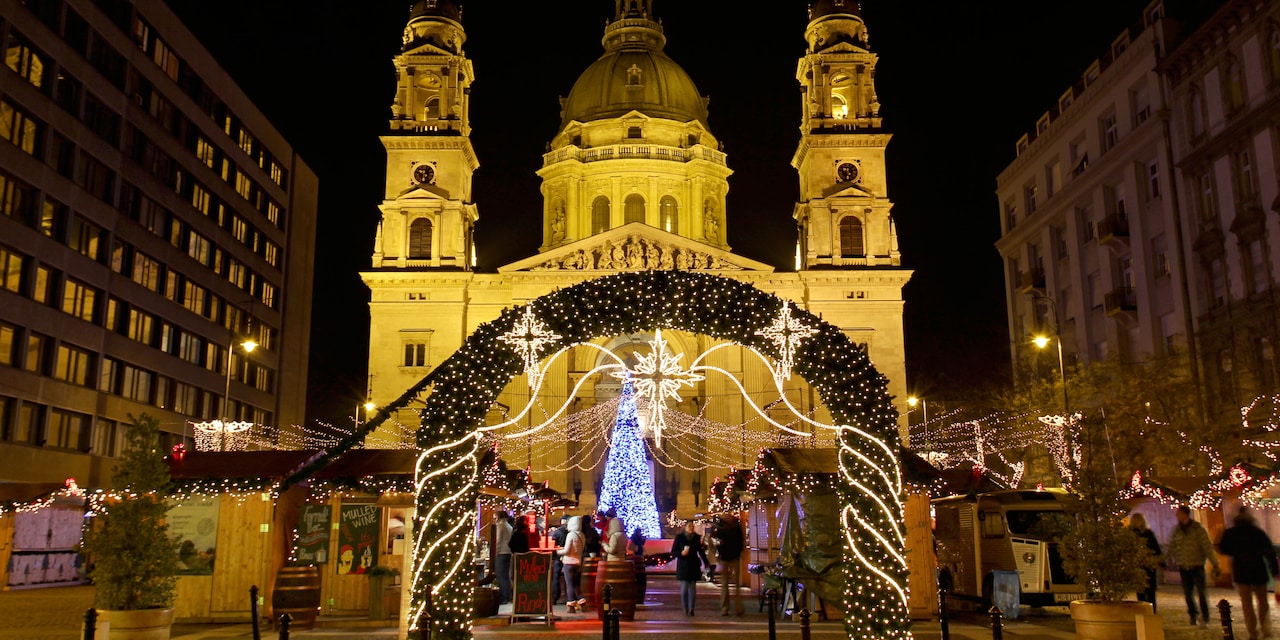 A Christmas Market in front of a church, with a lit Christmas tree and a holly archway A Christmas Market in front of a church, with a lit Christmas tree and a holly archway