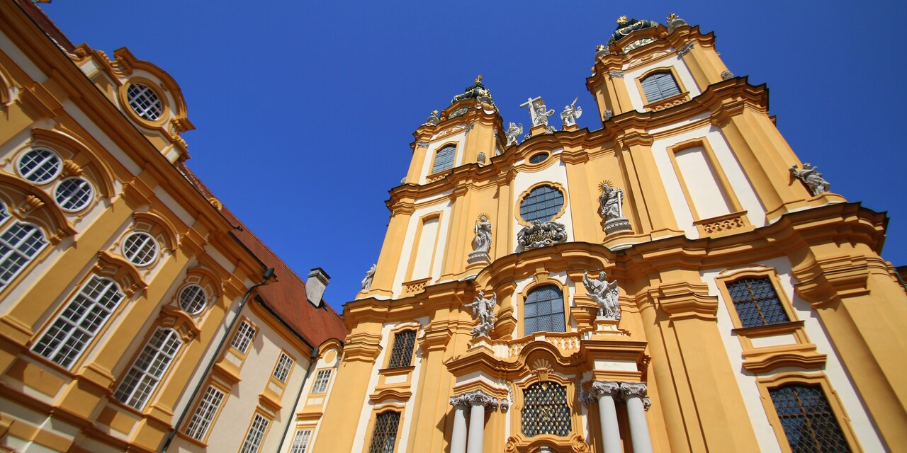 An impressive abbey with a cross and statues adorning the building An impressive abbey with a cross and statues adorning the building