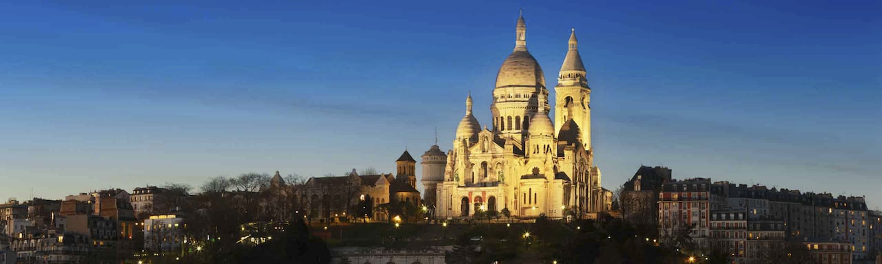 The Basilica of the Sacré Cœur is lit up high on Montmartre at dusk The Basilica of the Sacré Cœur is lit up high on Montmartre at dusk