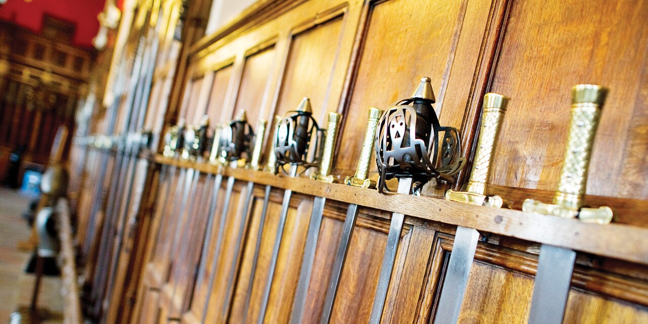 Medieval swords on display hanging on the wood panels of a castle wall Medieval swords on display hanging on the wood panels of a castle wall