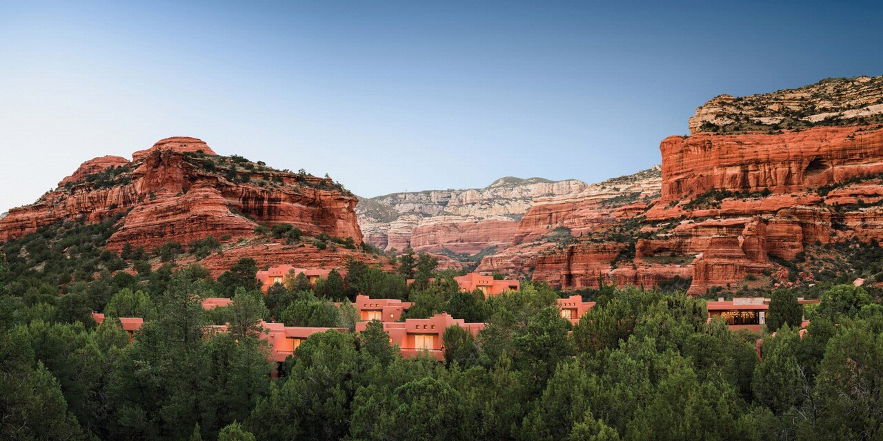 Adobe buildings in a shrub forest area, flanked by mesas Adobe buildings in a shrub forest area, flanked by mesas