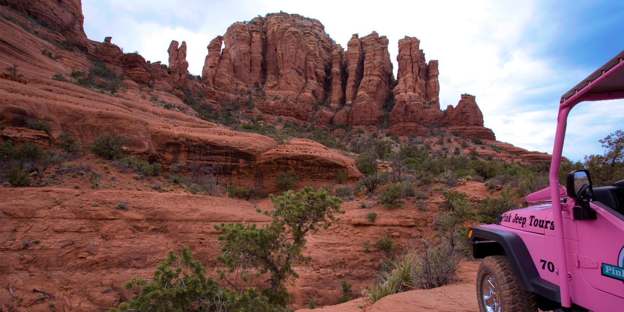 An off-road jeep faces buttes and rock formations An off-road jeep faces buttes and rock formations