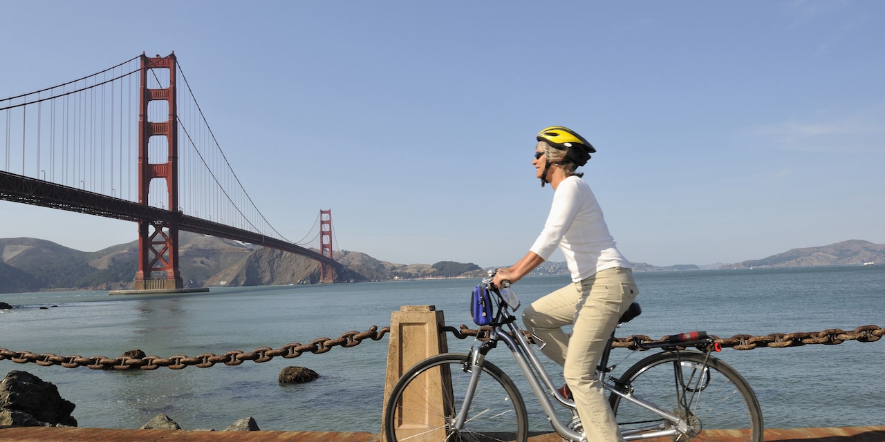 A woman rides a bike alongside San Francisco Bay near the Golden Gate Bridge A woman rides a bike alongside San Francisco Bay near the Golden Gate Bridge