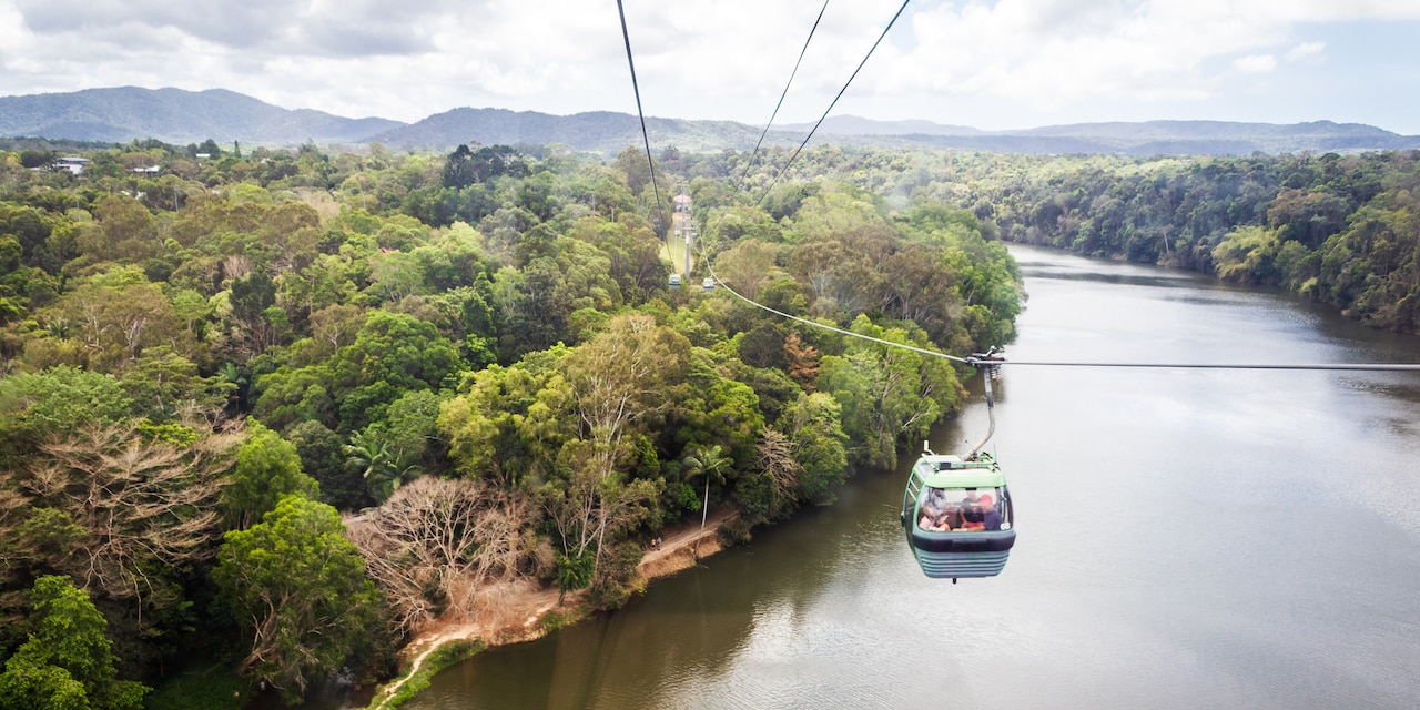 Several gondolas on the skyrail over a river and trees Several gondolas on the skyrail over a river and trees