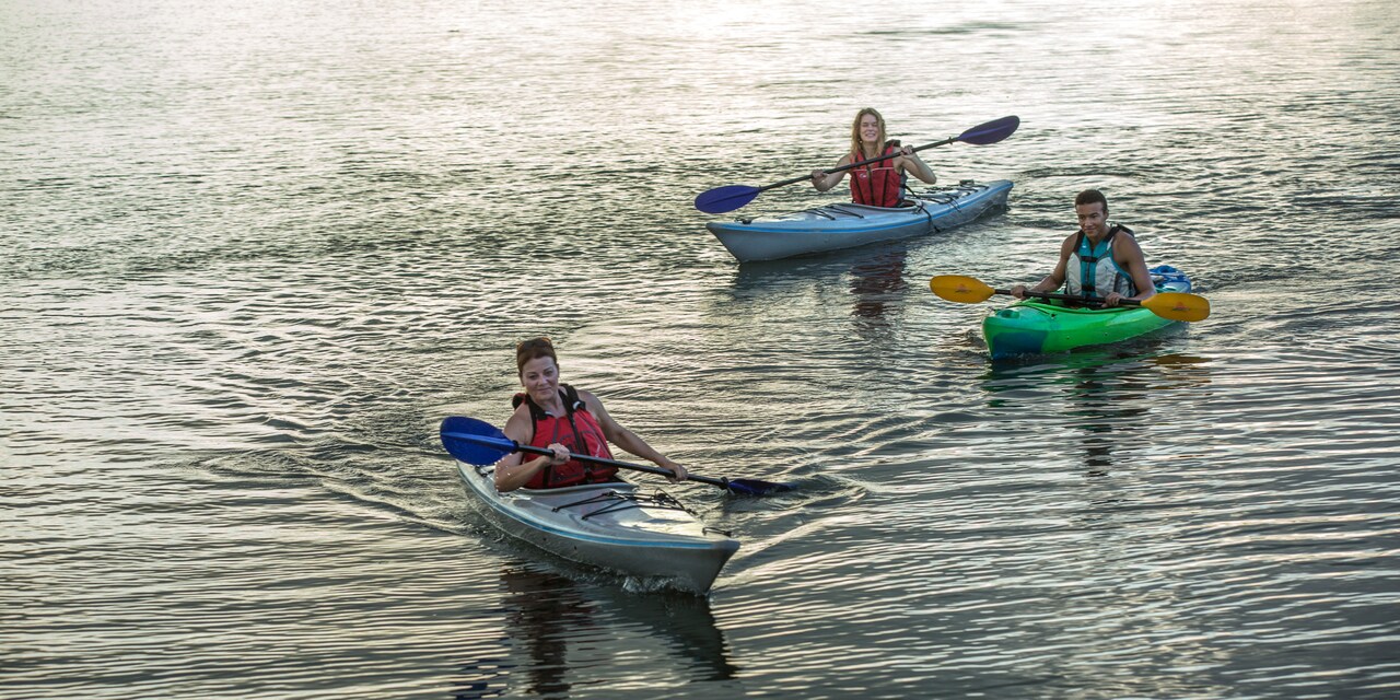 Two women and a man paddle kayaks on the water Two women and a man paddle kayaks on the water