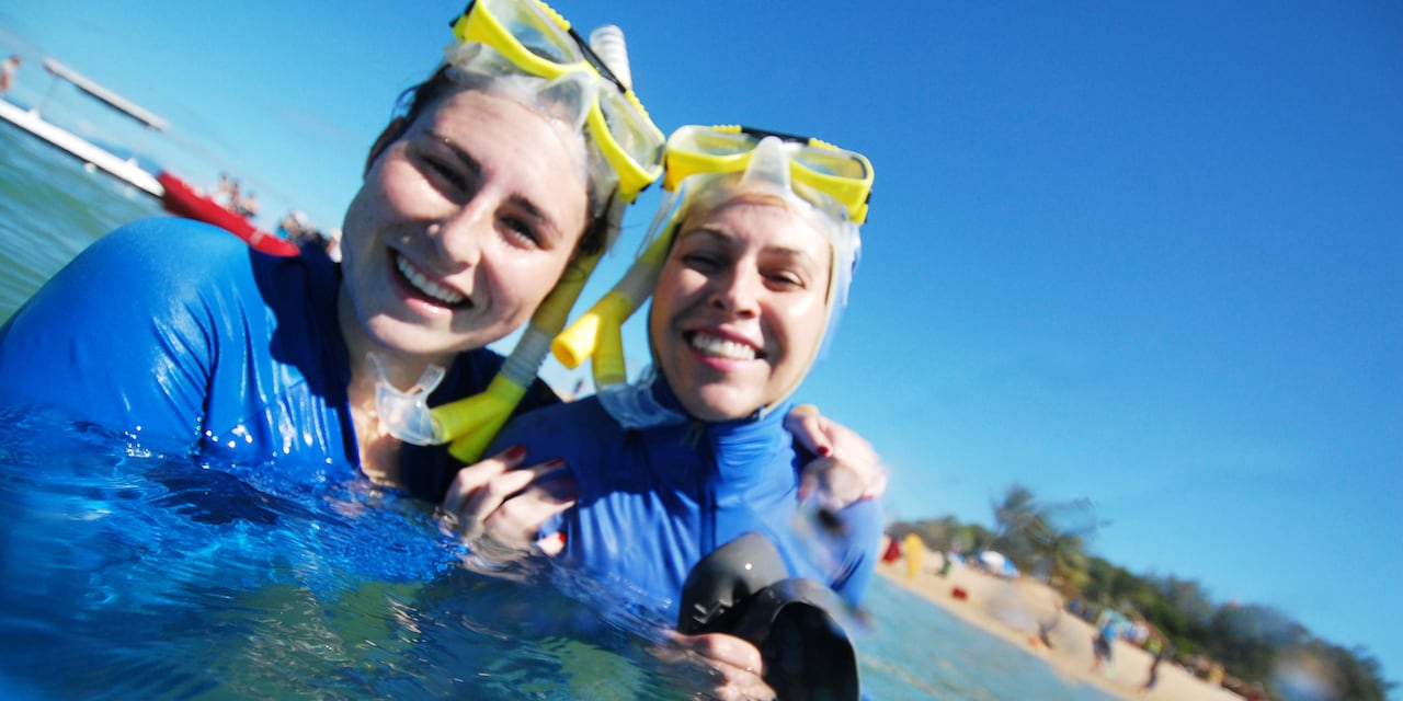 2 smiling teenage girls dressed in wet suits tread water and hold snorkel gear 2 smiling teenage girls dressed in wet suits tread water and hold snorkel gear