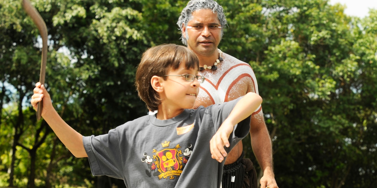 An aboriginal watches a boy throw a boomerang An aboriginal watches a boy throw a boomerang