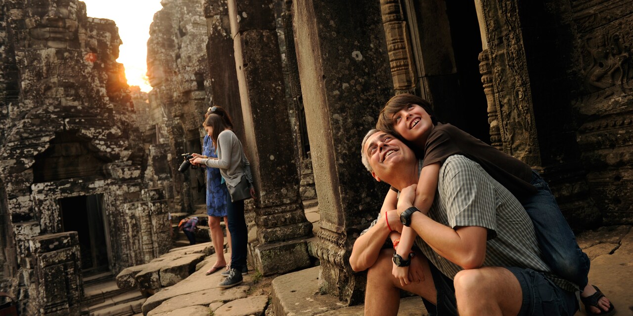 A father and son embrace while sitting in an ancient ruin