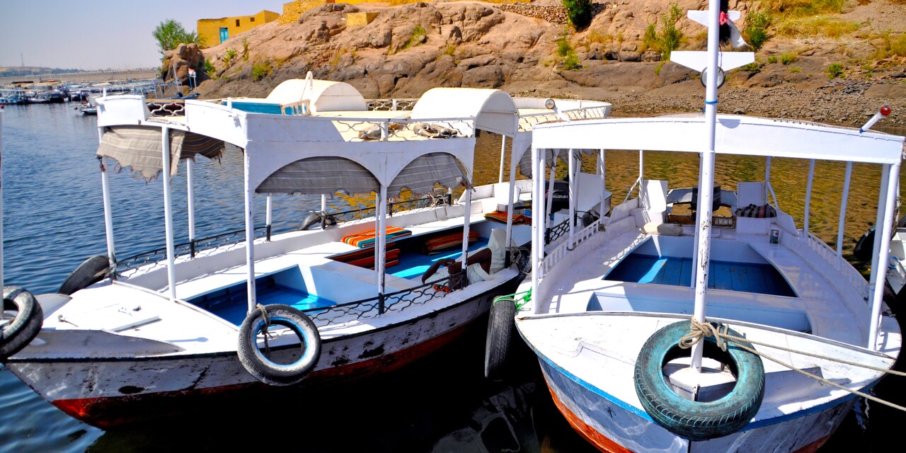 Two covered boats anchored off the shore of a seaside village Two covered boats anchored off the shore of a seaside village