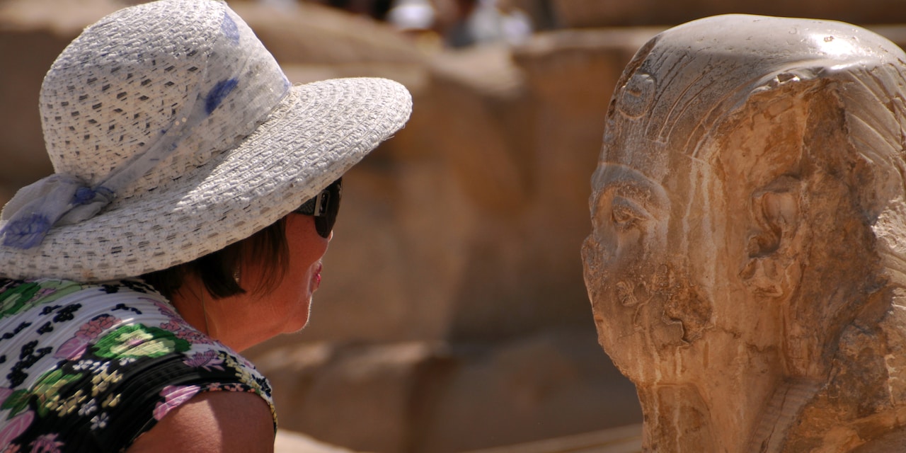 A woman in a hat takes a close-up look at a sculpture in the Valley of the Kings