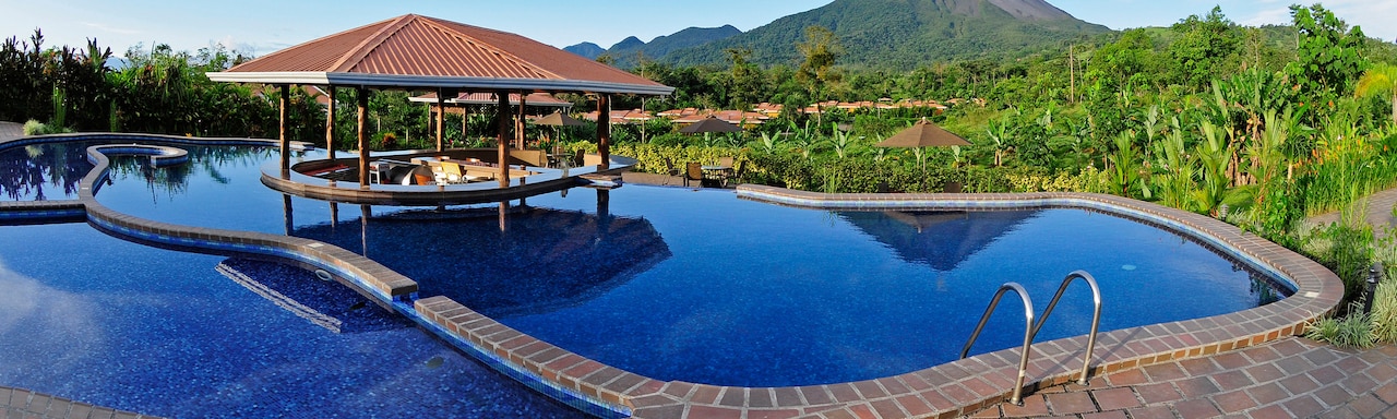 The pool at the Hotel Arenal Manoa with a swim-up bar in the middle and view of Arenal Volcano in the distance The pool at the Hotel Arenal Manoa with a swim-up bar in the middle and view of Arenal Volcano in the distance