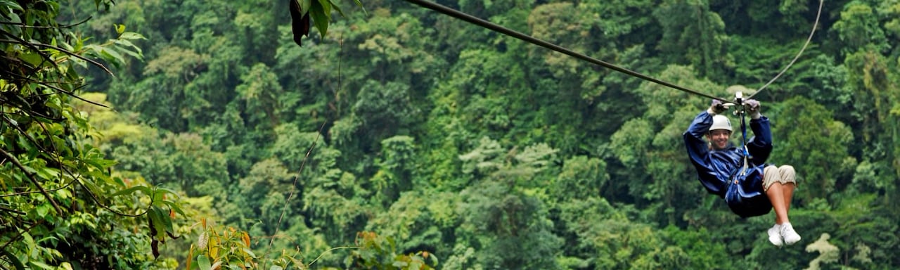 A tourist zip lines through the rainforest