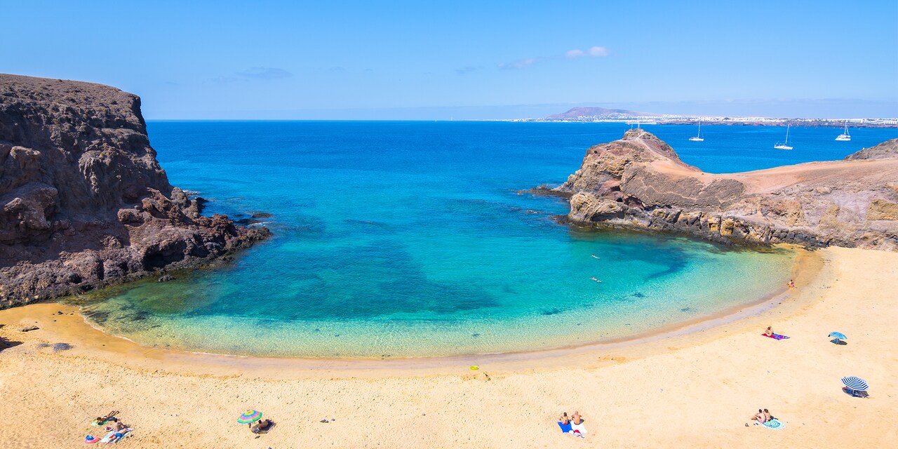 Horseshoe shaped beach with some umbrellas and sunbathers dotting the sand Horseshoe shaped beach with some umbrellas and sunbathers dotting the sand