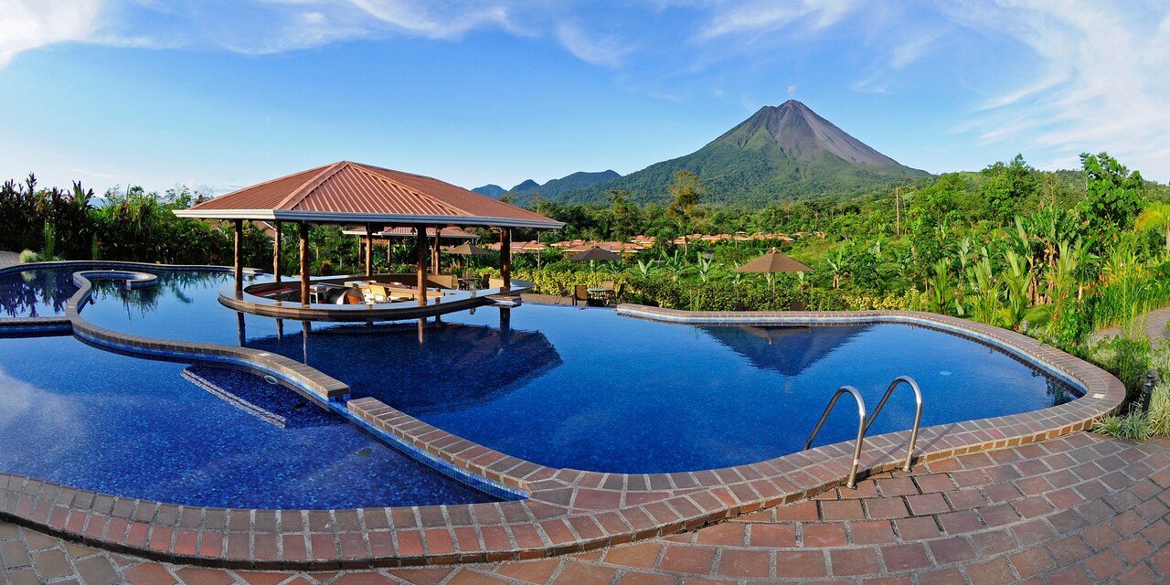 The pool at the Hotel Arenal Manoa with a swim-up bar in the middle and view of Arenal Volcano in the distance The pool at the Hotel Arenal Manoa with a swim-up bar in the middle and view of Arenal Volcano in the distance