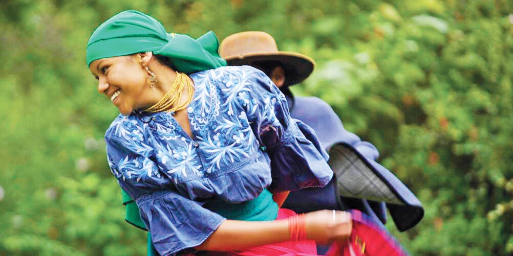A female Ecuadorian dancer in traditional costume twirls in front of a male dancer A female Ecuadorian dancer in traditional costume twirls in front of a male dancer