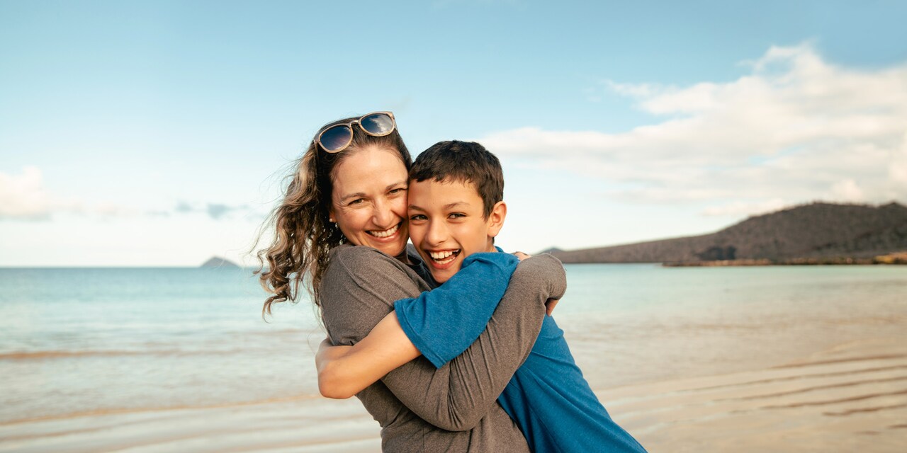 A woman hugs a young boy near the sea A woman hugs a young boy near the sea