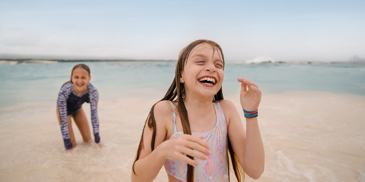 Two young girls are all smiles as they play in the water on a beach