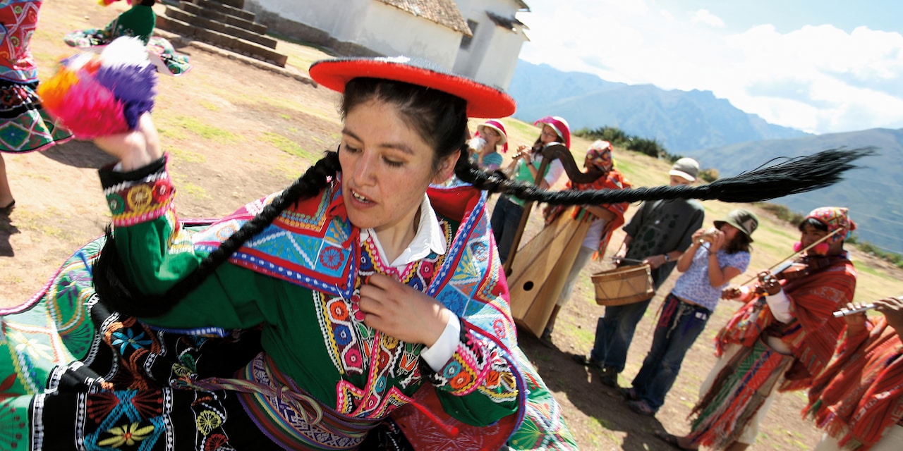 A woman wearing a traditional costume dances while a traditional band plays A woman wearing a traditional costume dances while a traditional band plays