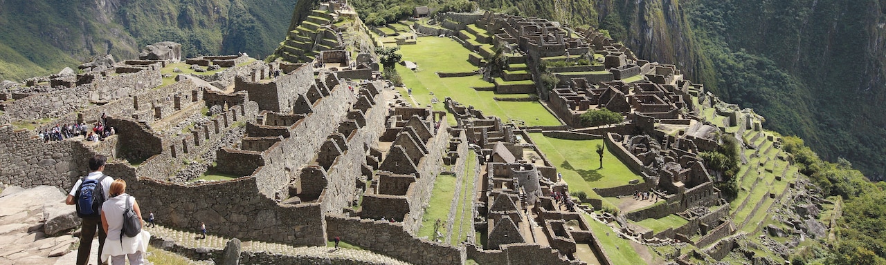 A couple stands on a stone terrace above Machu Picchu
