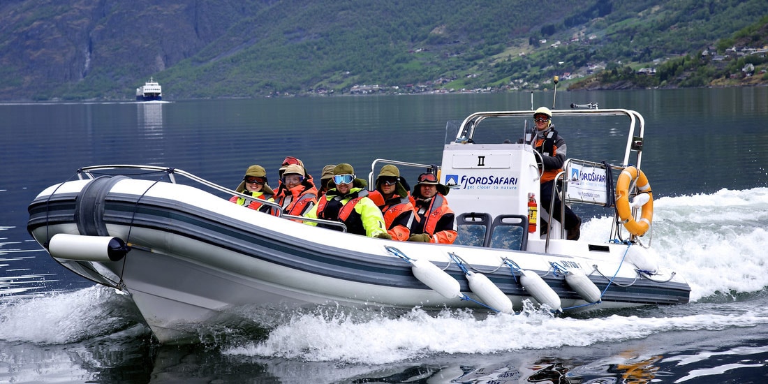 Tourists cruise across a fjord on a rigid inflatable boat