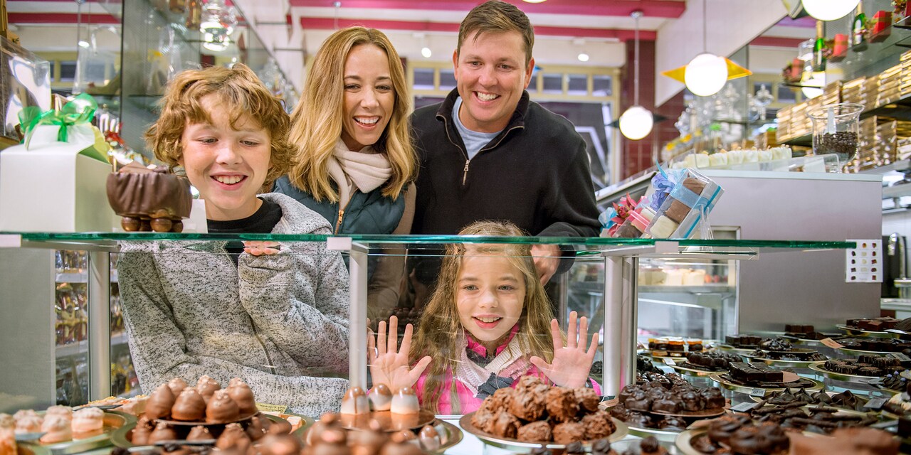A family of 4 looks at a display of chocolates behind a glass case in a chocolate shop in Amsterdam A family of 4 looks at a display of chocolates behind a glass case in a chocolate shop in Amsterdam