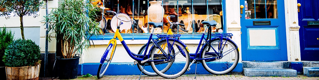 Two bicycles parked in front of a local shop Two bicycles parked in front of a local shop