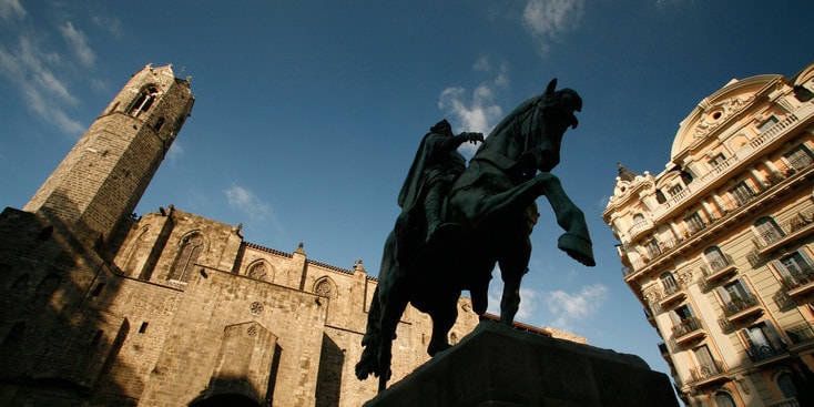 A monument of a king riding his horse surrounded by buildings A monument of a king riding his horse surrounded by buildings