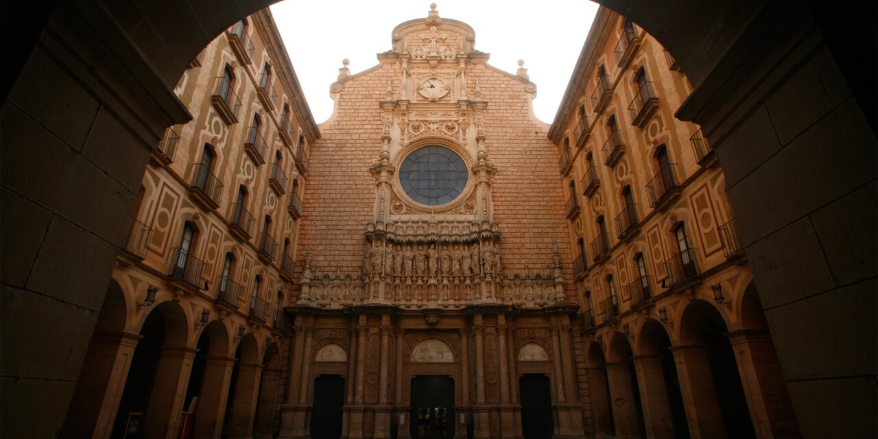 A view of the Santa Maria de Montserrat Abbey façade with its clock, round window and statues of the disciples A view of the Santa Maria de Montserrat Abbey façade with its clock, round window and statues of the disciples
