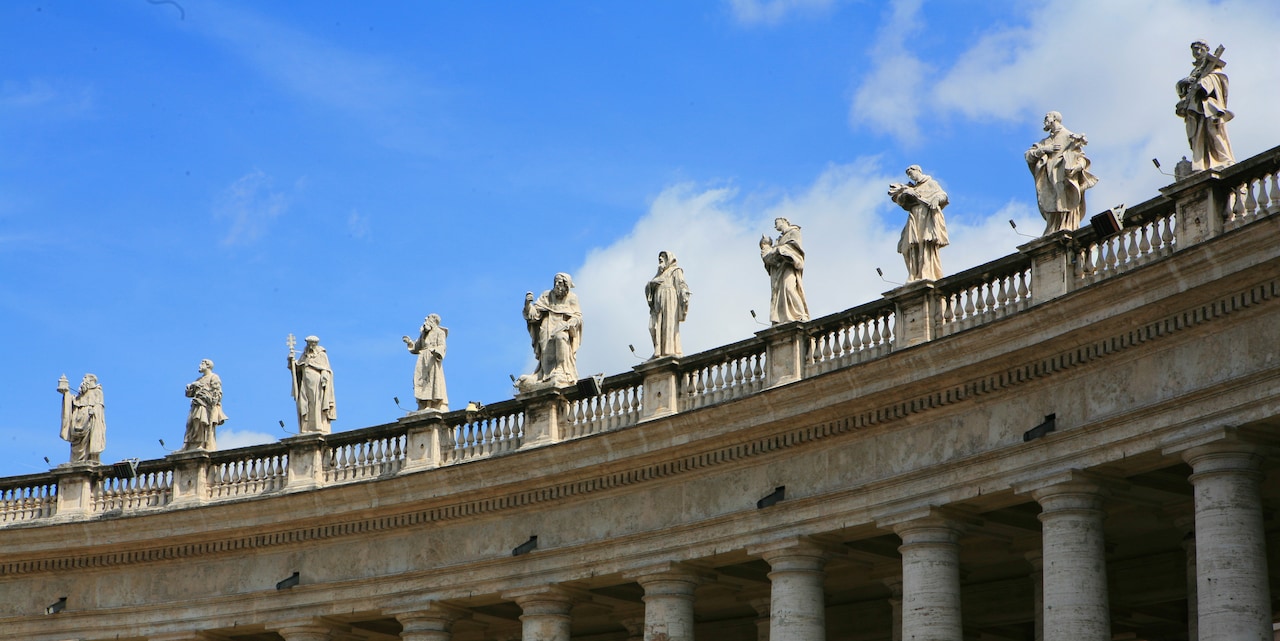 Statues stand atop the colonnades of St. Peter’s Basilica in Vatican City