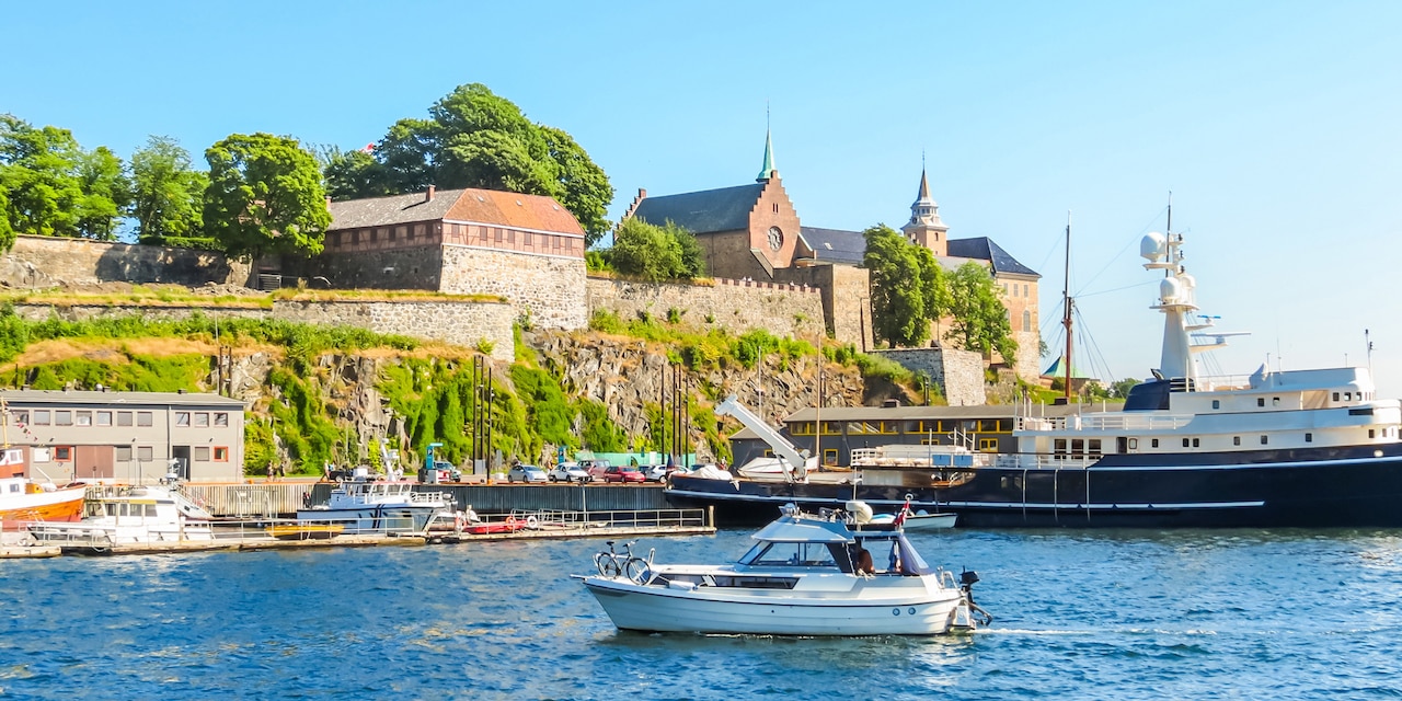 People walk across a bridge as a boat cruises below in the city of Oslo, Norway People walk across a bridge as a boat cruises below in the city of Oslo, Norway