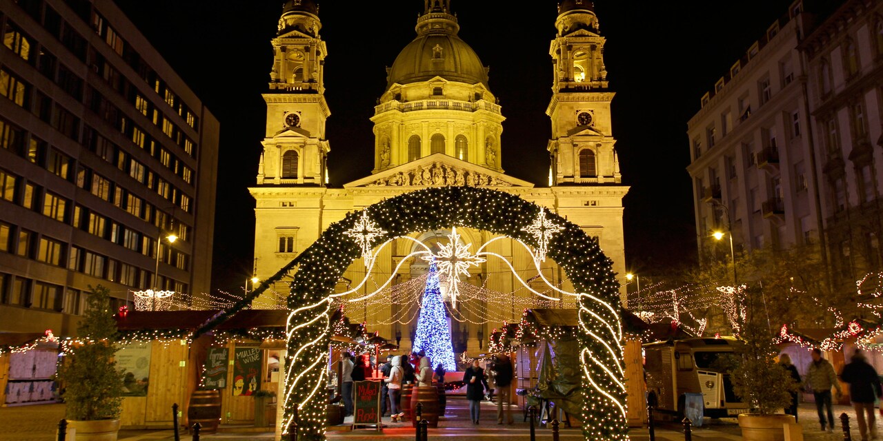 A Christmas Market in front of a church, with a lit Christmas tree and a holly archway
 
