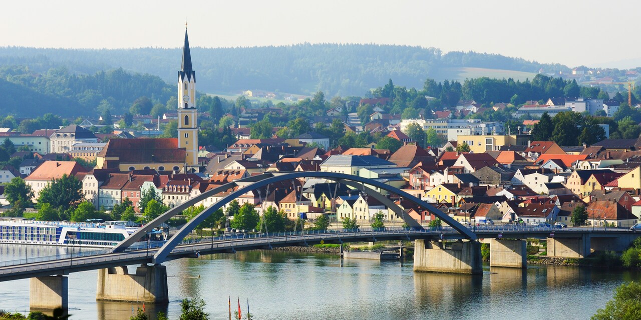 A bridge over a river and a quaint town with a steepled church on one side A bridge over a river and a quaint town with a steepled church on one side