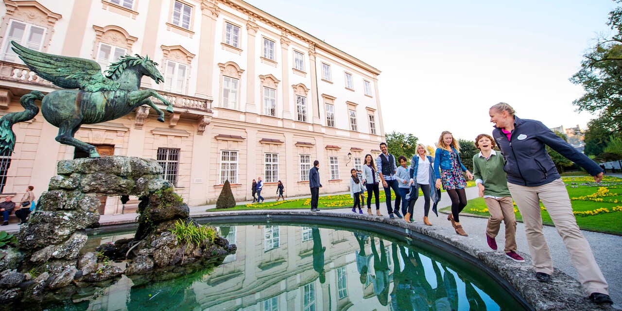 An Adventure Guide leads a family around a fountain with a statue of Pegasus at its center An Adventure Guide leads a family around a fountain with a statue of Pegasus at its center