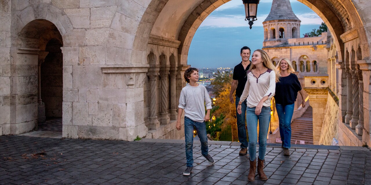 A family of 4 walks through a stone archway into a cobblestone courtyard of an old building A family of 4 walks through a stone archway into a cobblestone courtyard of an old building