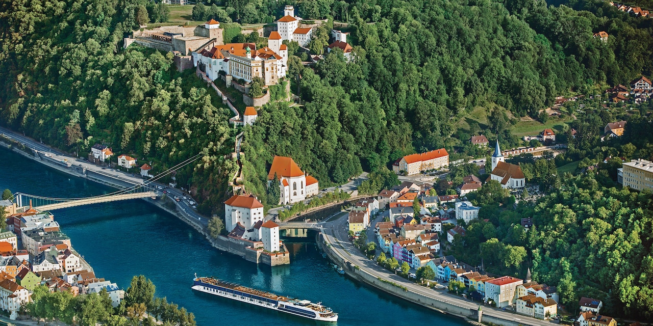 A river cruise ship sails on the Danube River through Passau, Germany and its lush landscape